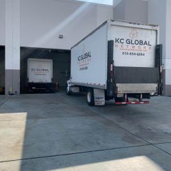 Image depicting the bustling activity at KC Global Network's Los Angeles warehouse with two of our trucks actively engaged in loading operations Cane and Organic Sugar